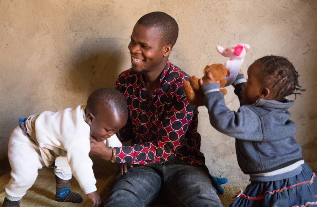 man laughing, playing with two children